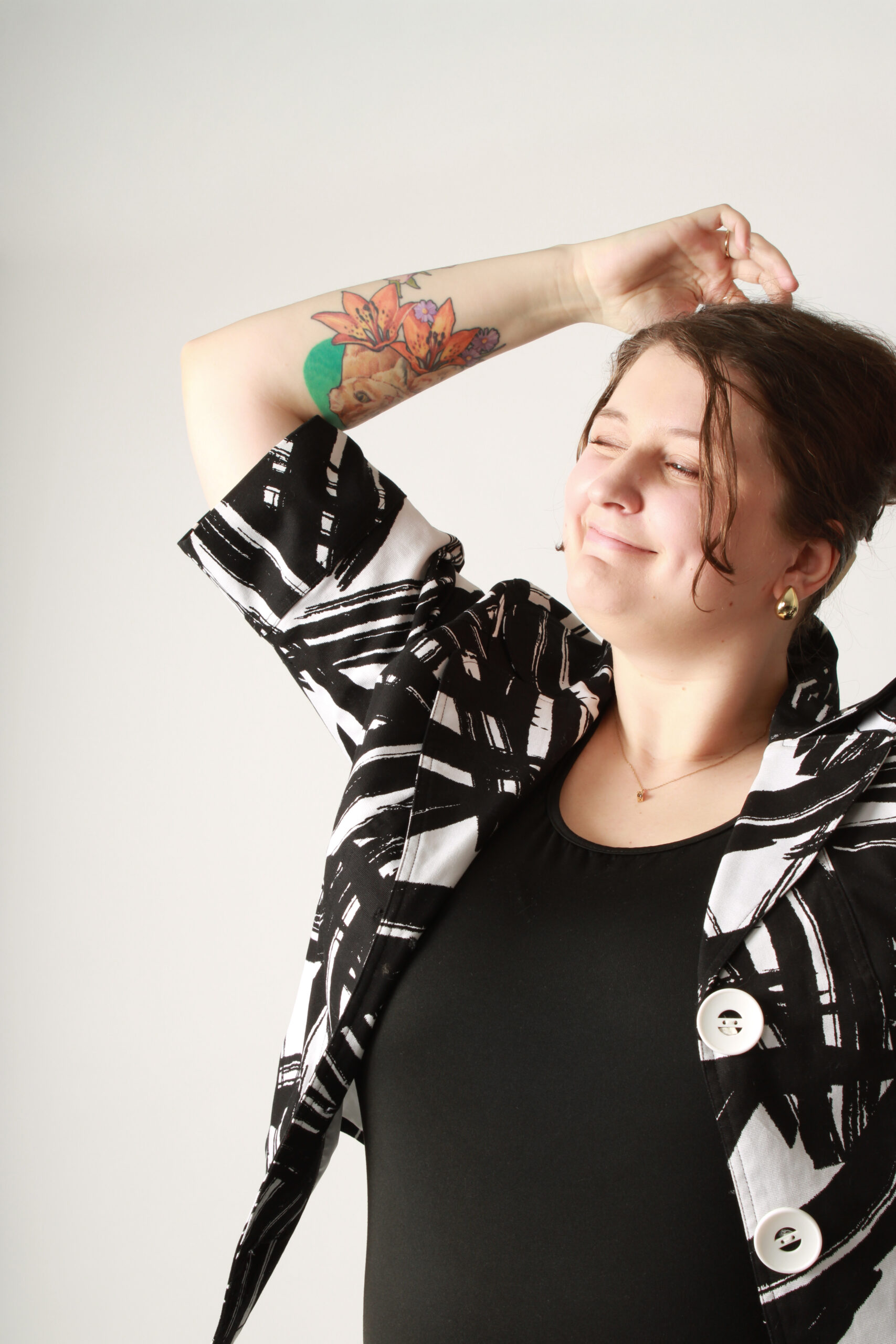 Madison (woman) in black and white jacket adjusting hair