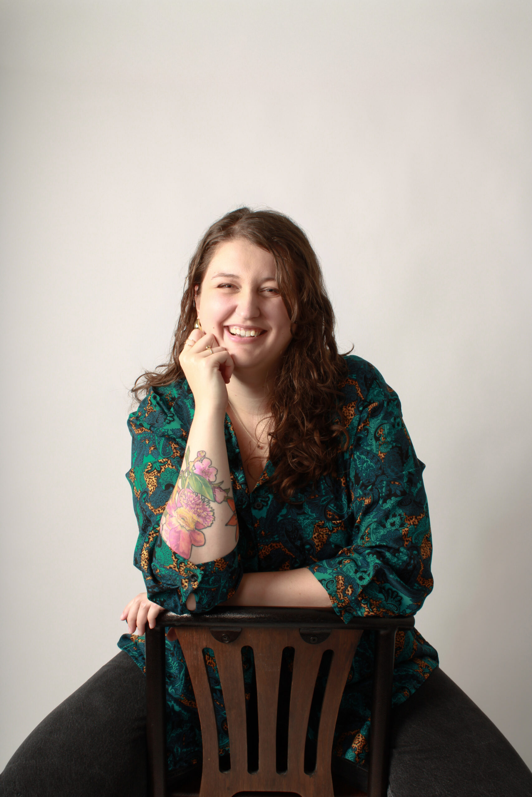 Madison (woman) with long brown hair sitting in a chair. Smiling facing to camera.